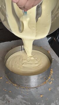 Pastry chef pouring liquid cheesecake filling into baking mold, preparing delicious dessert at home