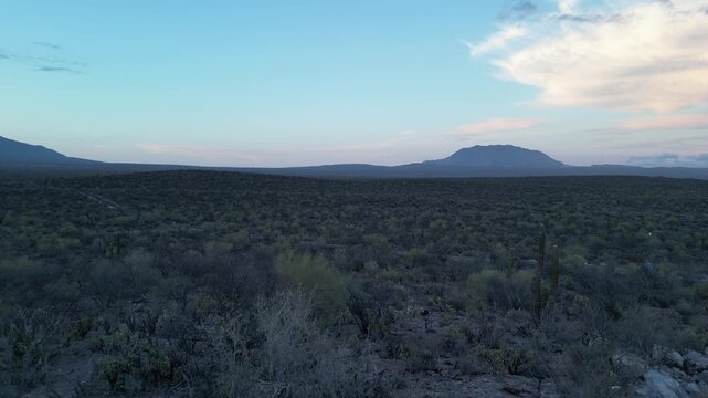 Aerial drone flyover shot moving along a road towards the mountains in the desert landscape of Baja California Sur during sunset