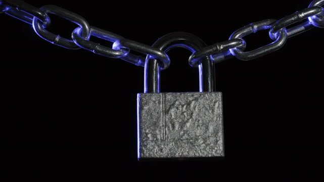 Locked padlock swinging on chain with flashing light from police flasher on black background, concept of detention, arrest