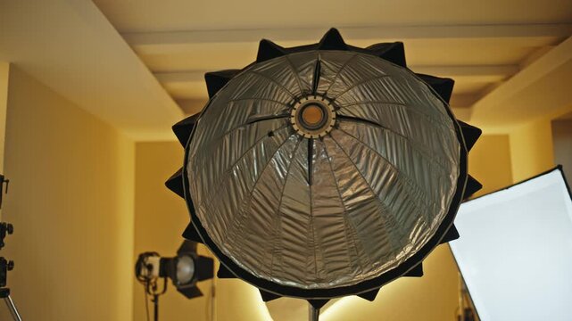Parabolic softbox light on stand in photography studio. Low angle lighting gear.
