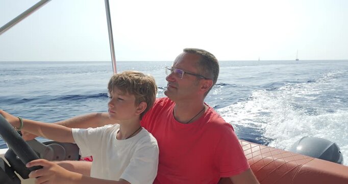 Father teaches son the driving of speed motor boat on the sea, enjoy time together in summer vacation