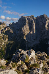 Obraz premium Rocky mountain foreground with dramatic rugged peaks and blue sky in warm afternoon sunlight in Montenegro