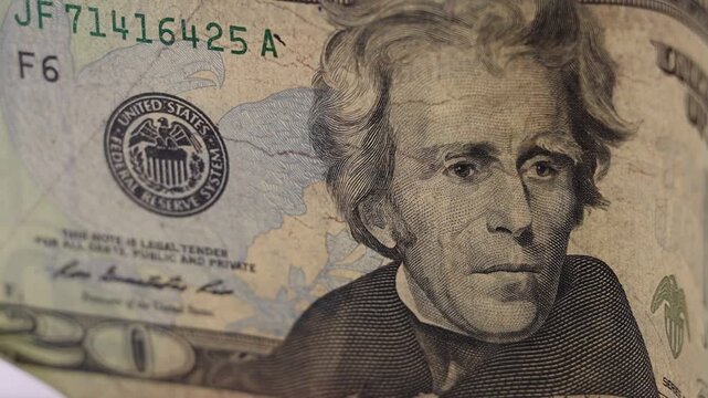 Close-up of an old $20 US dollar bill in rotation, highlighting its aged and detailed features.