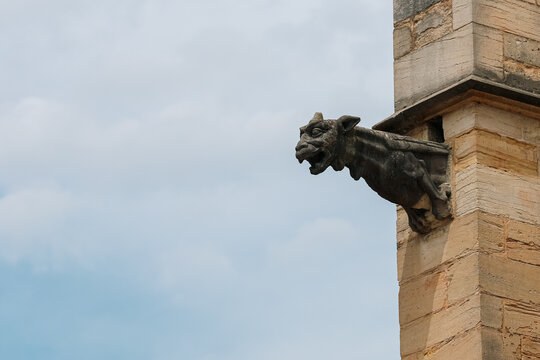 Stone gargoyle projecting from the historic church Coll&eacute;giale Notre-Dame de Beaunei in Burgundy, France, showcasing Gothic architecture and centuries of architectural craftsmanship.