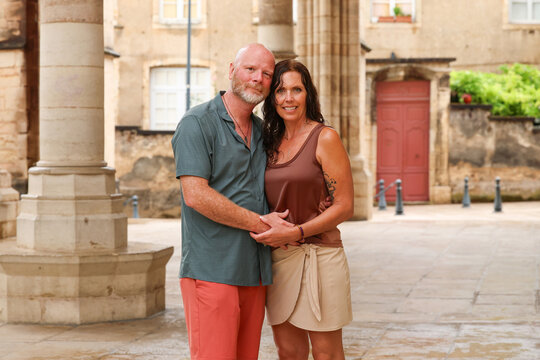 Couple standing beneath historic stone arches in Beaune, Burgundy, France, surrounded by classical architecture and the character of the old town.