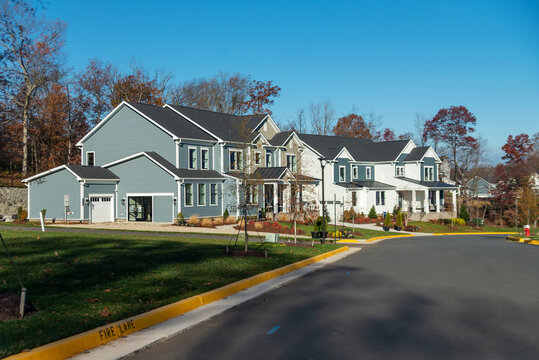 New homes line a landscaped curved street in suburban Leesburg Virginia.