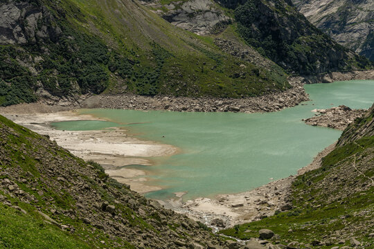Guttannen, Switzerland. Turquoise Gelmersee reservoir with exposed shoreline in the Bernese Alps viewed from alpine hiking trail