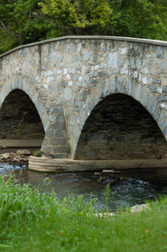 Stream Flows Under Stone Arched Bridge