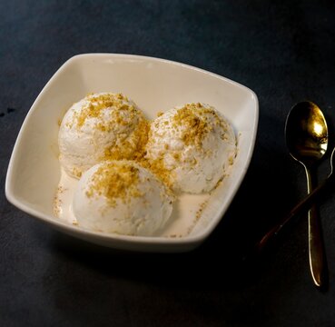 Bowl with tasty vanilla ice cream on a dark background