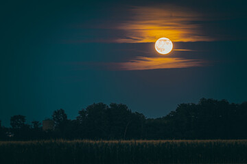 Full moon also know as Buck moon shining moonlight on night sky illuminating clouds © Blaž