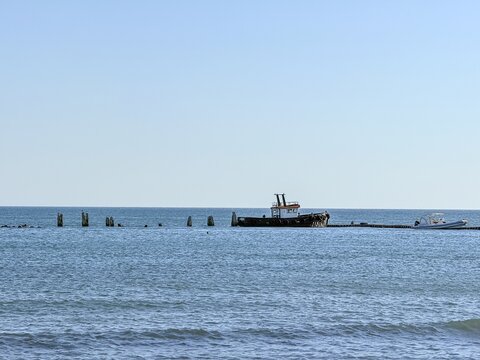 Small boat sailing across calm sea horizon under blue sky