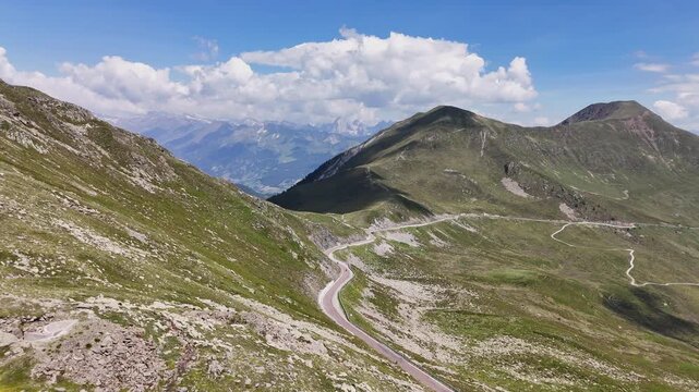Smooth aerial drone footage flying forward over a winding mountain road and green alpine slopes near Campo di Trens in South Tyrol, Italy.⁠