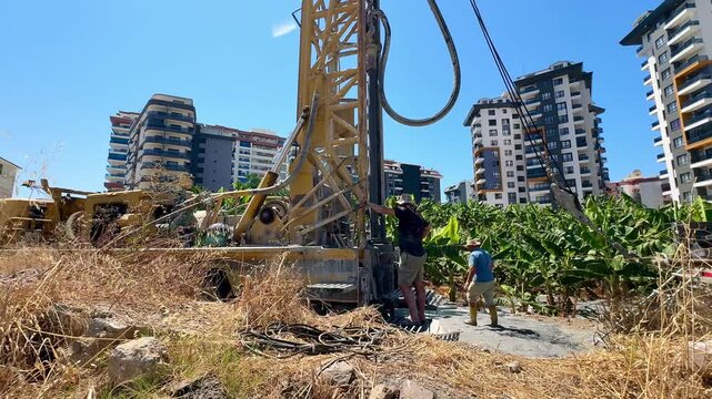 A well drilling operation in Turkey, surrounded by banana plantations and residential complexes in the background.