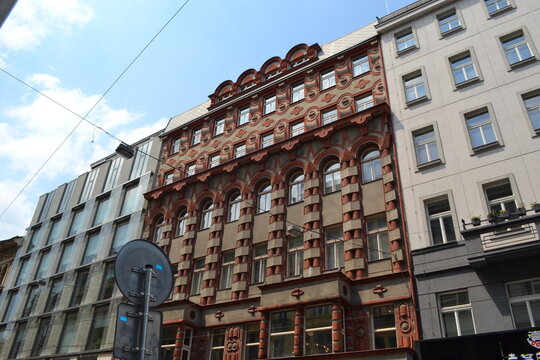 Red ornate early 20th century facade with patterned brick and arched windows in Prague for architectural background and urban poster design