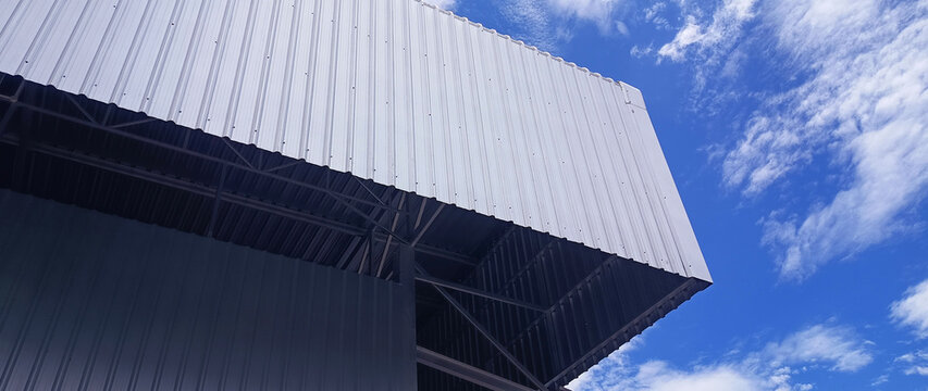 Metal sheet roof curve on blue sky. Modern construction, Metal ribbed arch span roof covering, Large building roof. not ai