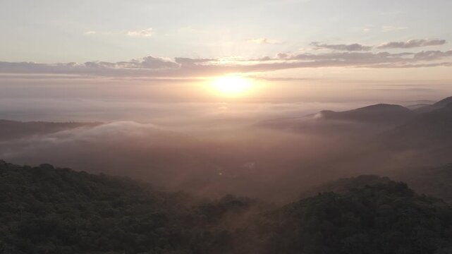Aerial drone moving left with sunrise and morning fog over Guag&uuml;&iacute; Mountain, La Vega, Dominican Republic