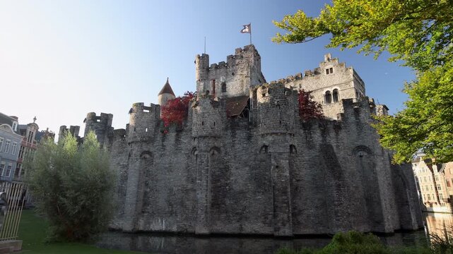 Gravensteen, a medieval castle in the city of Ghent in Belgium, Europe. Ancient Stone Castle with Moat and Green Trees on a Clear Day, Old European Architecture