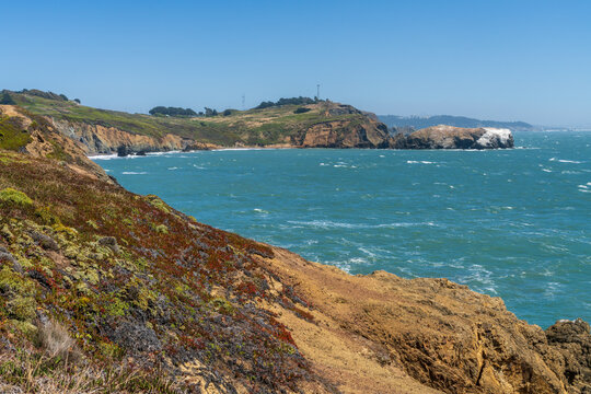 Waves crash against the dramatic rocky cliffs of the Marin Headlands overlooking the Pacific Ocean near the scenic Rodeo Beach coastal trail.
