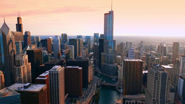 Flight over the Chicago River over high-rise buildings. Pink sky over the vast city panorama.