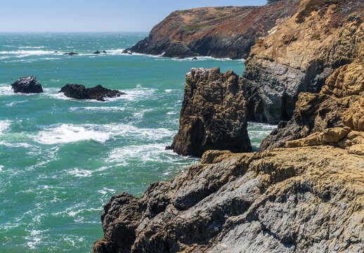 Waves crash against the dramatic rocky cliffs of the Marin Headlands overlooking the Pacific Ocean near the scenic Rodeo Beach coastal trail.