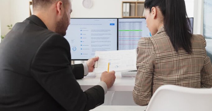 Business colleagues analysts in office reviewing data dashboard. Two professionals review reports on a computer screen, in meeting with charts. Strong corporate teamwork analytics concept