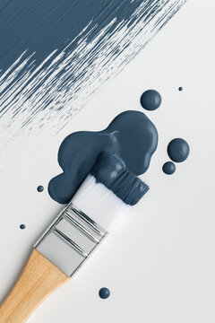 Paintbrush in a puddle of blue paint with drops and brush stroke