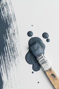 Paintbrush in a puddle of blue paint with drops and brush stroke