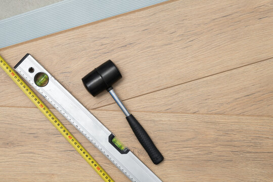 Rubber mallet and spirit level on wooden flooring planks