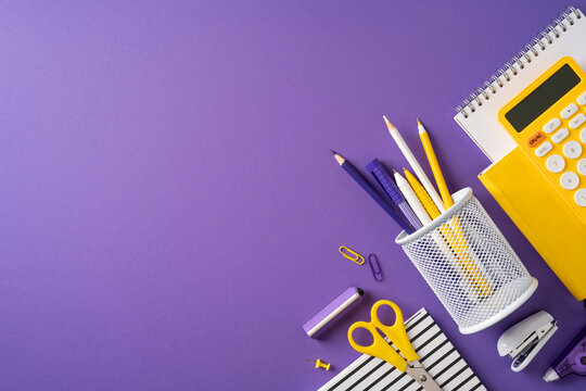 Back to school supplies on purple desk with organized stationery, calculator and pencil holder