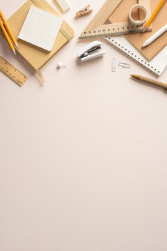 Neutral back to school stationery flat lay with notebooks pencils stapler and rulers on beige vertical tabletop