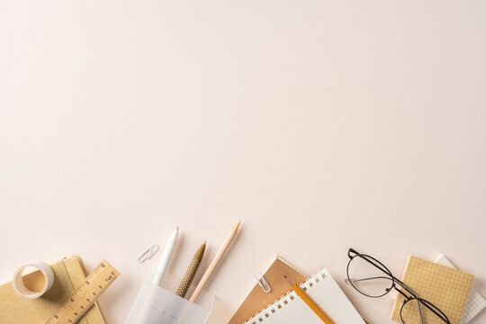 Back to school flatlay with stationery, notebooks, glasses and pencils on a neutral desk with space for text
