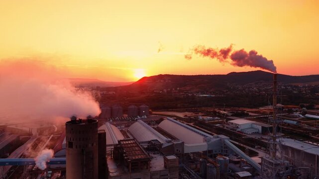 Modern industrial plant in the countryside. Smoke coves out of the pipes. Sunset time footage.