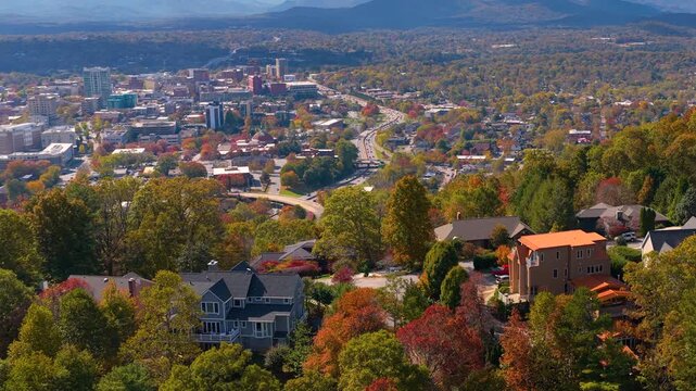 Scenic residential neighborhood near Asheville, North Carolina with hillside homes surrounded by brilliant autumn foliage and wooded mountain slopes.