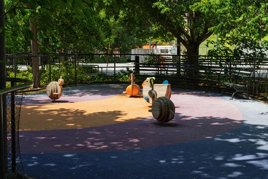 Empty playground with spring rider toys in shaded urban park