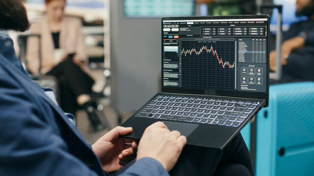 Businessman delegate monitoring trading data and stock exchange graphs on laptop in airport lounge, with a consultant tracking financial forecast and investment trends while waiting near gate.