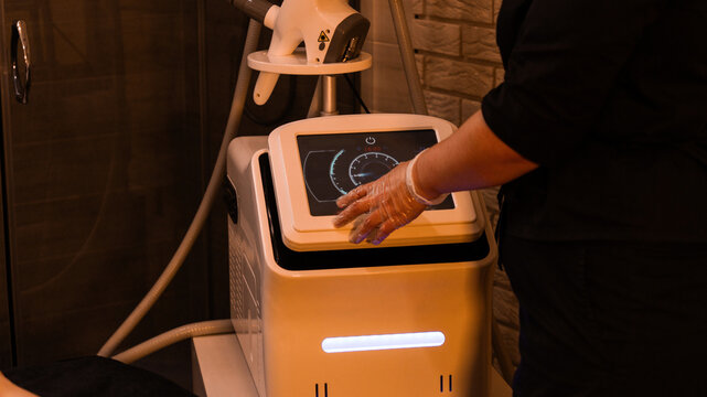 masseuse adjusts massage device. Vacuum roller massage. Dim atmospheric warm light. self-care, grooming, weight loss