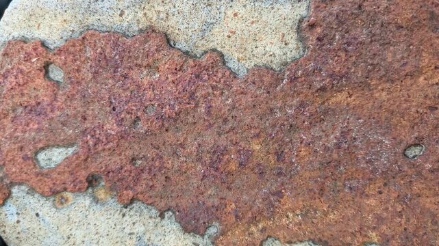 Weathered coastal rock surface displaying natural mineral patterns, rugged texture, and erosion formed by marine conditions.