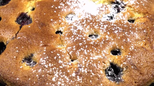 Dusting with powdered sugar of freshly baked pie with fresh blueberries, top view, background
