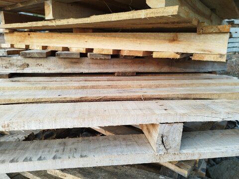 Stacked wooden pallets lie idle, weathered and worn