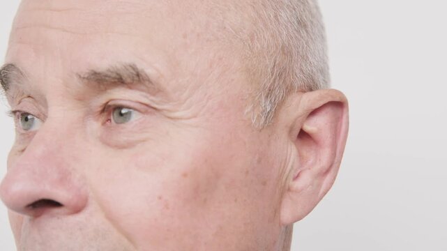 Close up mature senior man ear treatment with medical spray, oil drops, prevention earwax plug, Male receiving ear care, earwax buildup, infection prevention, auditory health, cleaning routine