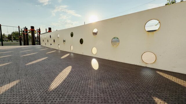 An empty ping pong table rests on a bright playground. Warm sunlight shines through the metal net, bringing a cheerful and nostalgic feeling. The quiet scene feels completely peaceful.