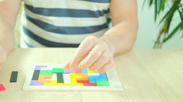 caucasian mature man 60-65 years old manipulating wooden geometric shapes intellectual puzzle, potential mental activity in preventing dementia and Alzheimer's disease, Keeping mind sharp