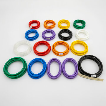 Collection of colored coiled tubing with size labels and a transparent tube on white plastic colorful