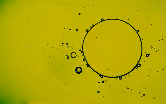 Yellow oil drop surrounded by bubbles on surface
