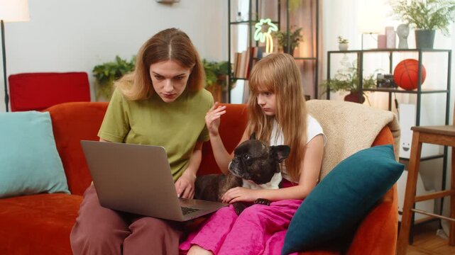 Mother and daughter with French bulldog at home face laptop error virus glitch restart attempt feel stress. Woman and girl with dog on sofa try reboot run scan seek fix antivirus update calm support.