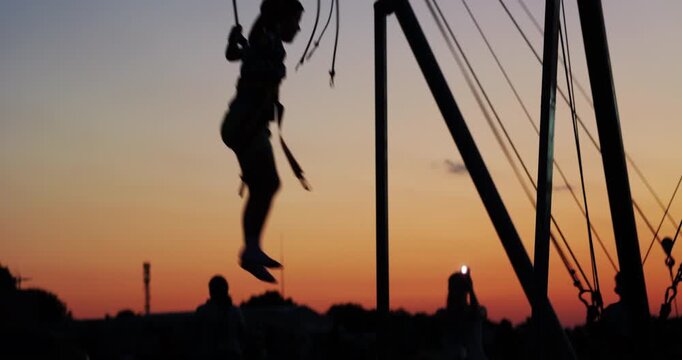 Sunset silhouettes of kids jumping in trampoline