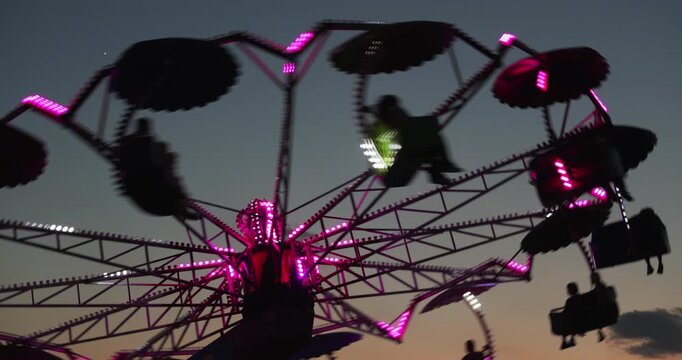 Paratrooper umbrella ride spinning, sunset silhouette