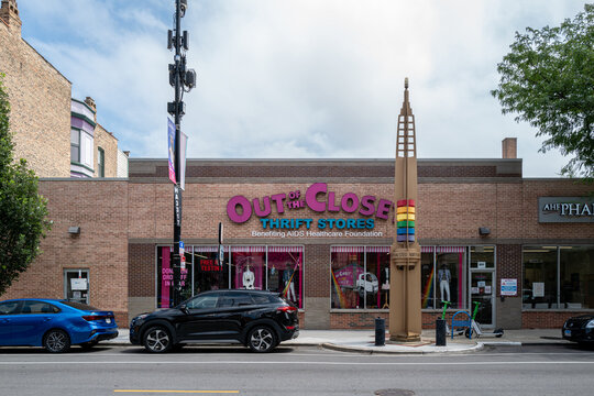 Out of the Closet thrift store storefront and Legacy Walk rainbow pylon in Chicago's Northalsted neighborhood, illustrating LGBTQ+ community activism and non-profit retail. Chicago, IL - July 2026