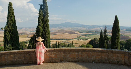 Naklejka na ściany i meble Woman enjoying tuscany val d'orcia landscape with cypress trees