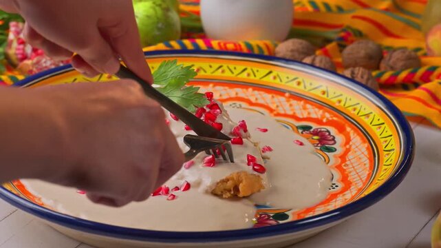 Person cutting traditional Mexican chile en nogada with knife and fork